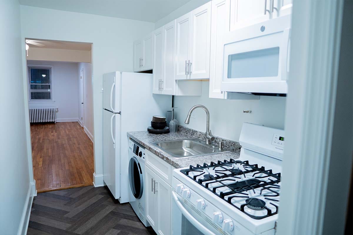 New sink, countertop, stove, microwave and white cabinets installed by JVV Remodeling inside an apartment kitchen located in Washington DC