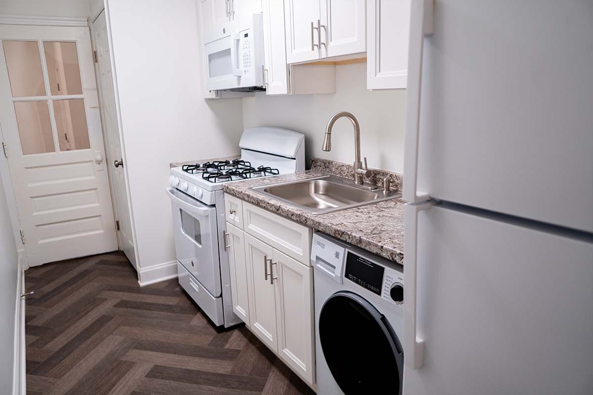 Wide view at new countertop, sink, cabinet and stove installed inside an apartment kitchen by JVV Remodeling
