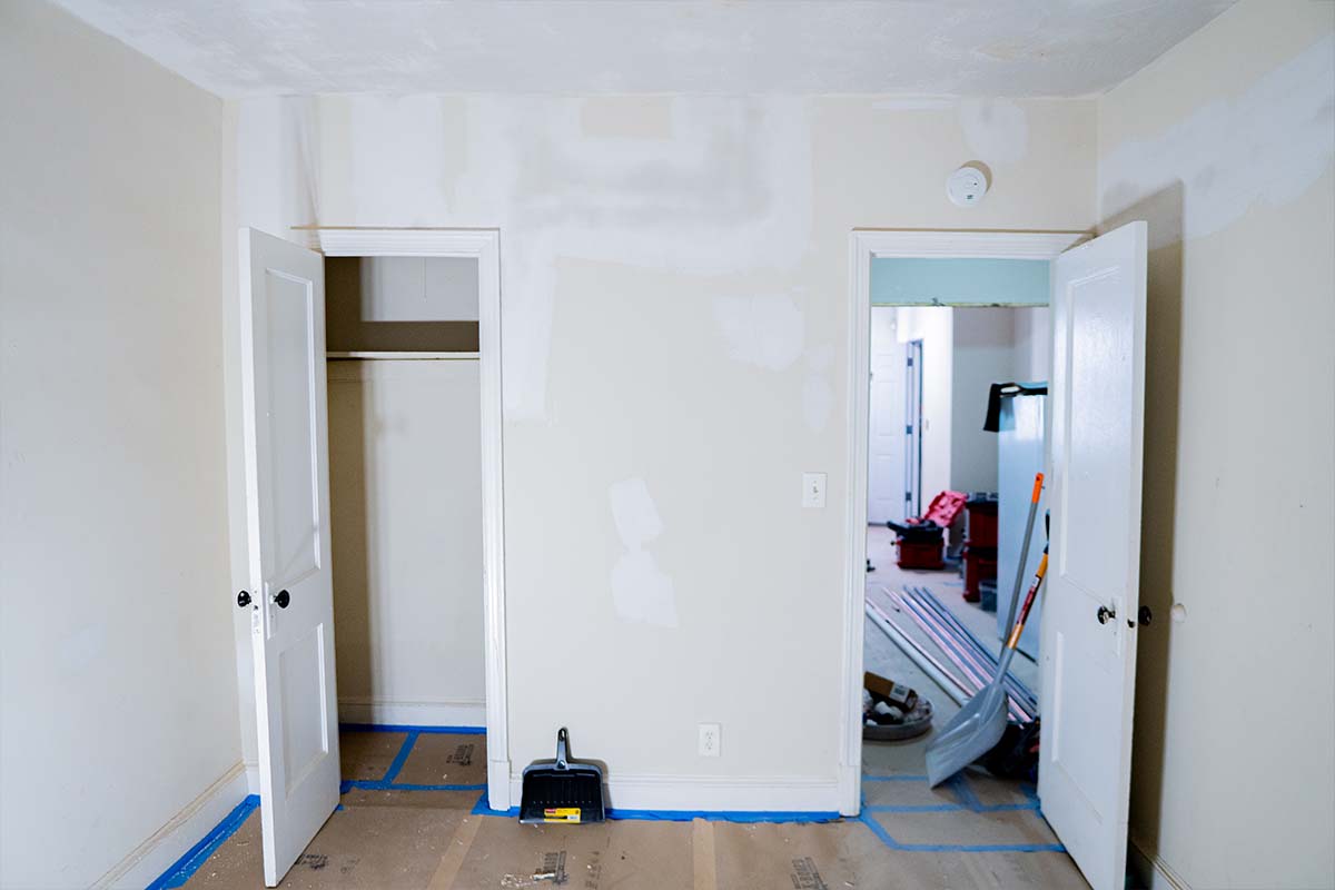 Wide view of an apartment bedroom with plaster patches all across the walls ready for sanding
