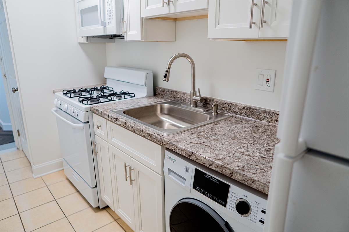 closeup on new marble countertop, white cabinets and sink installed in an apartment kitchen