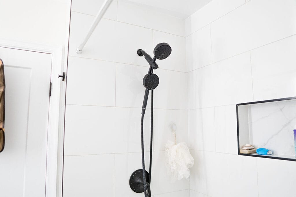 New black shower head installed in a tub and shower inside a hallway bathroom in Virginia